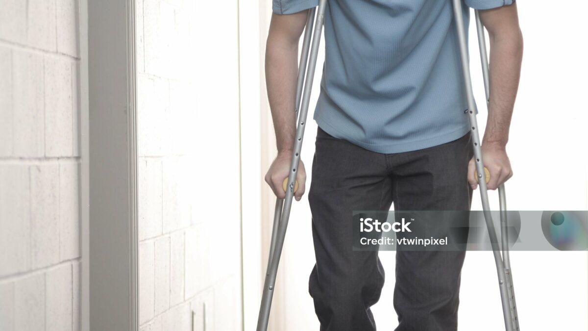 Young man using crutches in hospital.